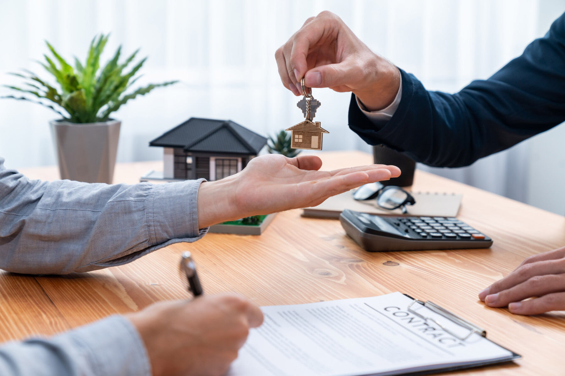 Real estate agent handing house key to buyer after signing rental least contract during house loan meeting. Successful property sale purchase agreement for new home ownership. Entity